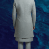 A man stands against a textured blue background, wearing a dove grey Indo-Western sherwani with intricate embroidery, paired with a matching kurta and trousers.