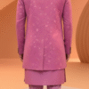 A man wearing a pink embroidered Indo-Western sherwani with a brooch and matching pants.