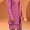 A man wearing a pink embroidered Indo-Western sherwani with a brooch and matching pants.