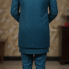 A man wearing a teal blue Indo-Western suit with a long jacket and matching pants, standing indoors.