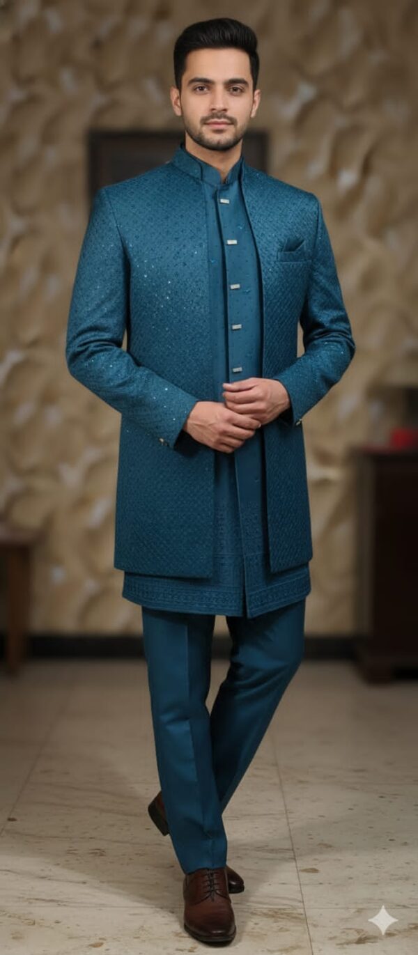 A man wearing a teal blue Indo-Western suit with a long jacket and matching pants, standing indoors.