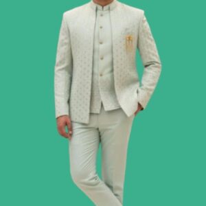 A man wearing a pastel mint green Indo-Western sherwani set with subtle textured embroidery, paired with matching trousers and ethnic juttis, styled with a Mandarin collar and gold brooch.