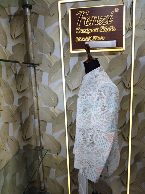 “White embroidered Jodhpuri suit with intricate pastel patterns displayed on a mannequin at Fenzi Designer Studio.”