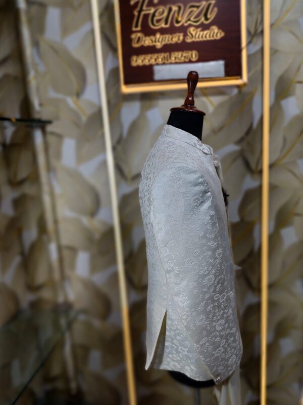 Cream-colored embroidered Jodhpuri suit displayed on a mannequin at a designer studio.