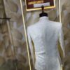Cream-colored embroidered Jodhpuri suit displayed on a mannequin at a designer studio.