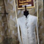 Cream-colored embroidered Jodhpuri suit displayed on a mannequin at a designer studio.